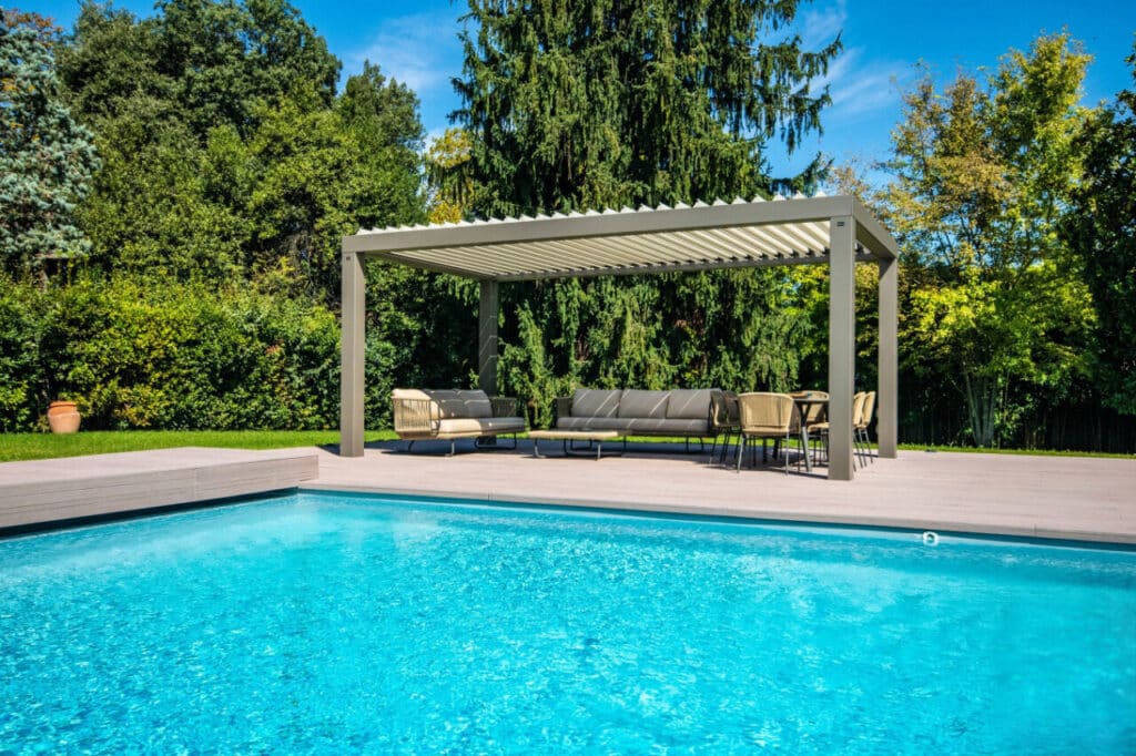 Pergola bioclimatique aluminium sur terrasse en bois, installée au bord d'une piscine à Ancenis.