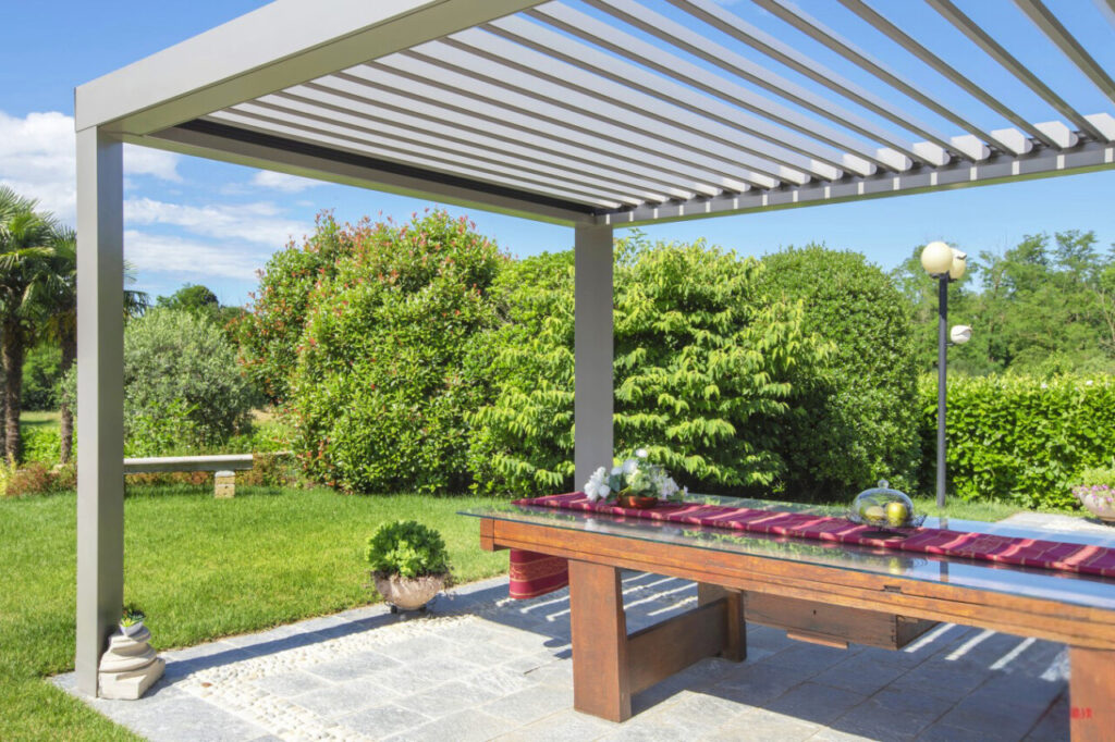 Pergola bioclimatique autoportante en aluminium installée dans un jardin à Candé avec table de repas.
