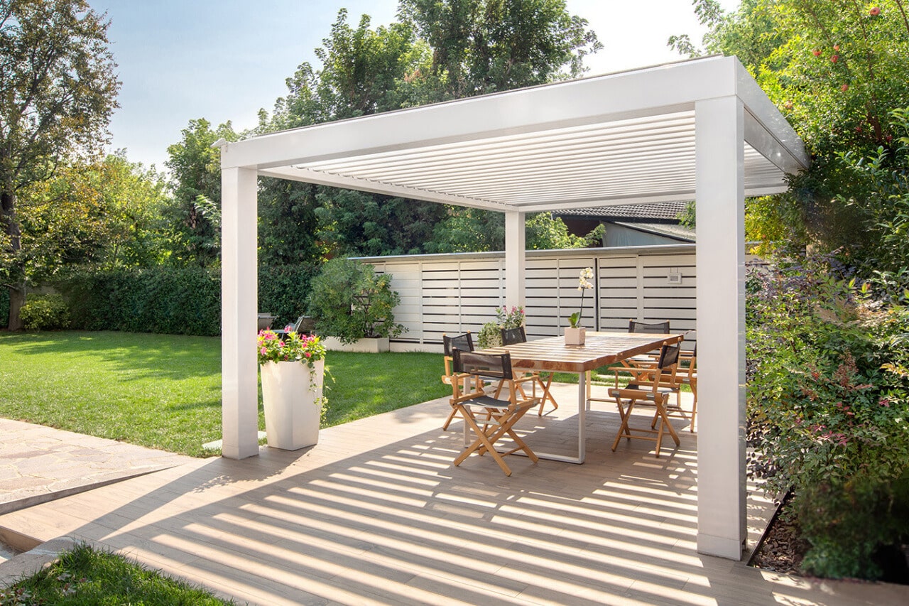 Espace repas sous une pergola bioclimatique autoportante blanche à Montjean-sur-Loire, sur terrasse dalles.