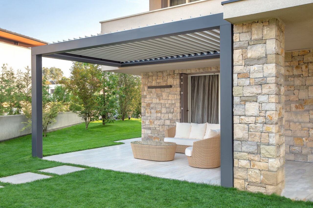 Pergola bioclimatique étanche en aluminium adossée à une maison en pierre à Saint Augustin des Bois.