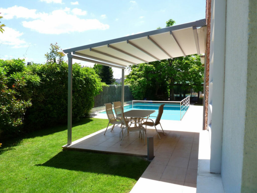 Pergola à toile rétractable adossée à une maison à Bouchemaine, protégeant une terrasse près d'une piscine.