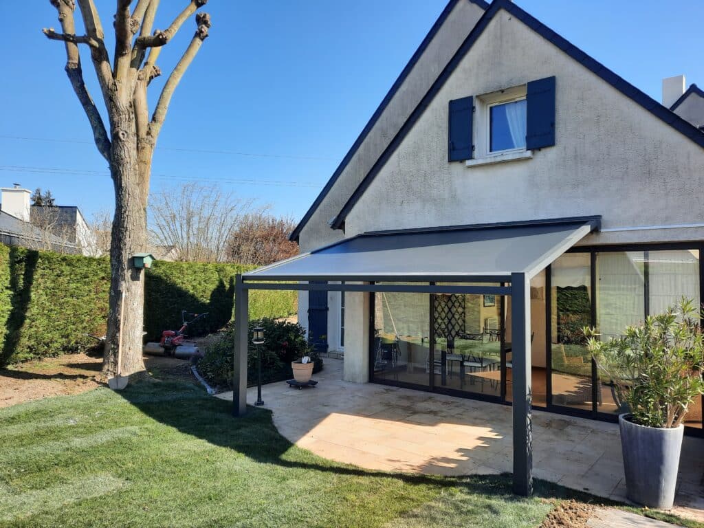 Pergola à toile ouverte offrant de l’ombre sur une terrasse pavée à Montreuil-Juigné.