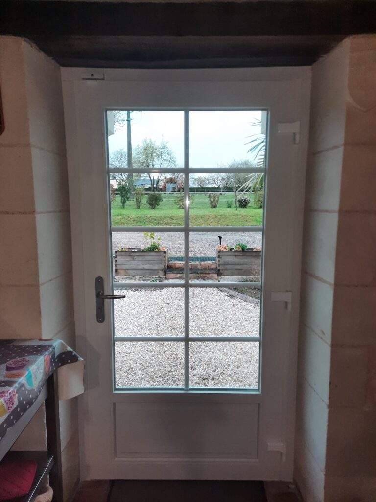 Porte d’entrée PVC blanche avec vitrage clair et petits bois intégrés, vue intérieure à Mazé.