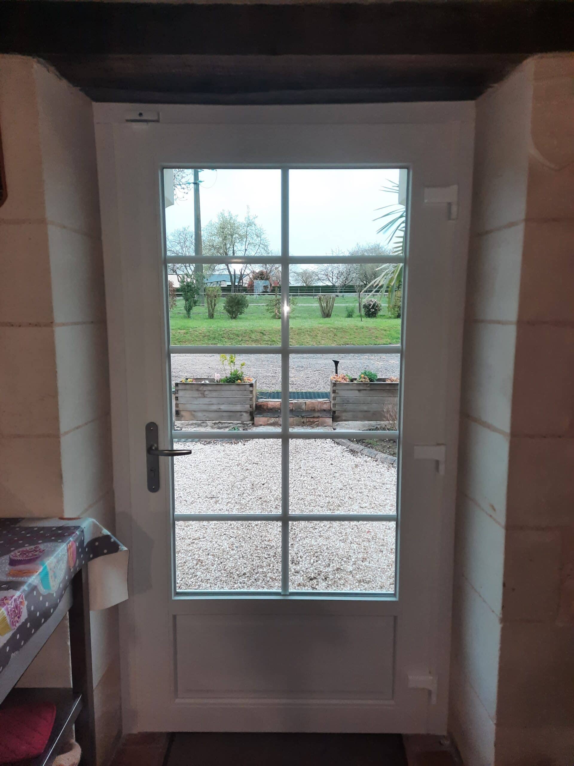 Porte d’entrée PVC blanche avec vitrage clair et petits bois intégrés, vue intérieure à Mazé.