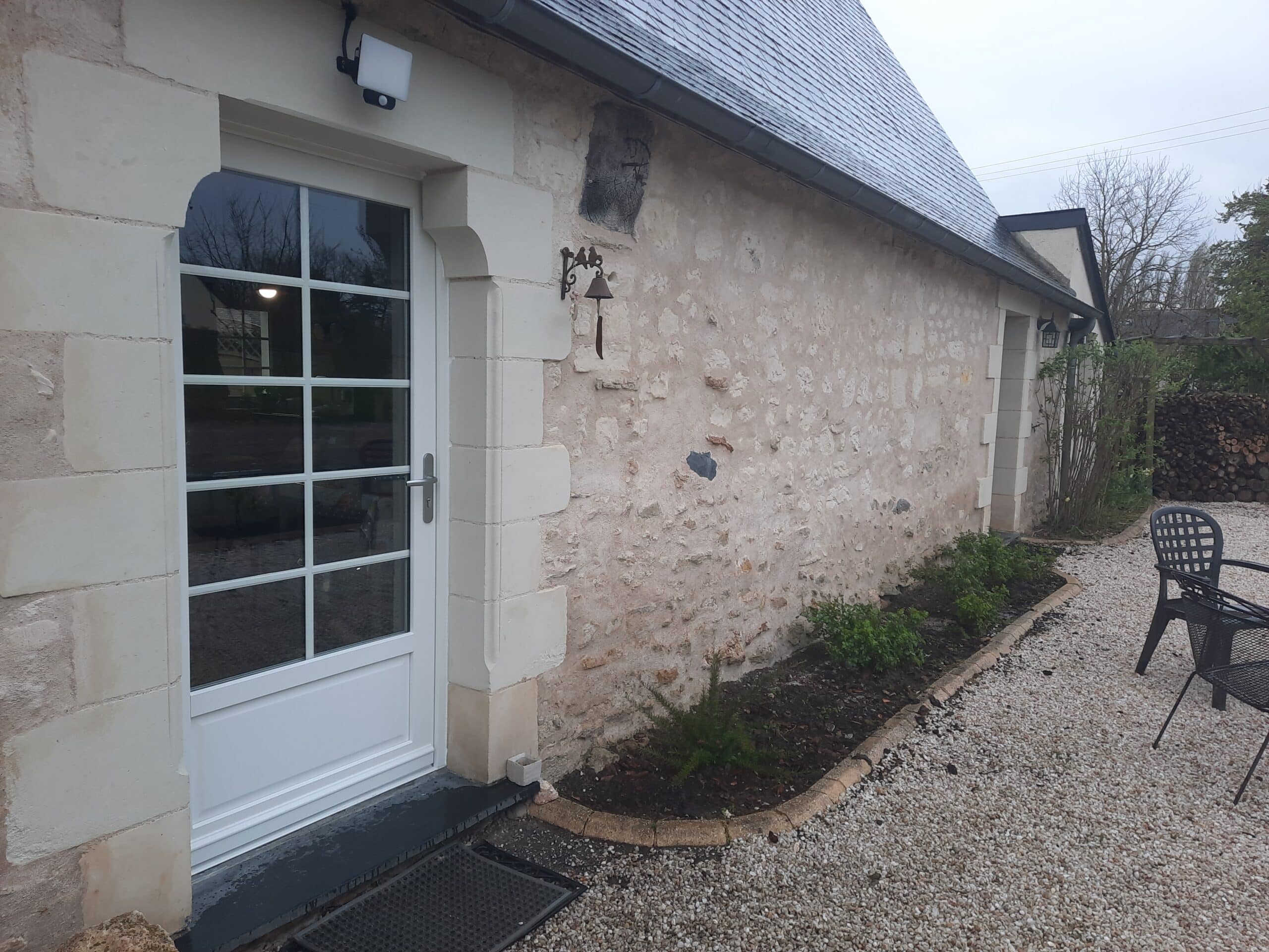 Vue de la porte d’entrée PVC sur façade en pierre naturelle à Mazé, avec seuil PMR.