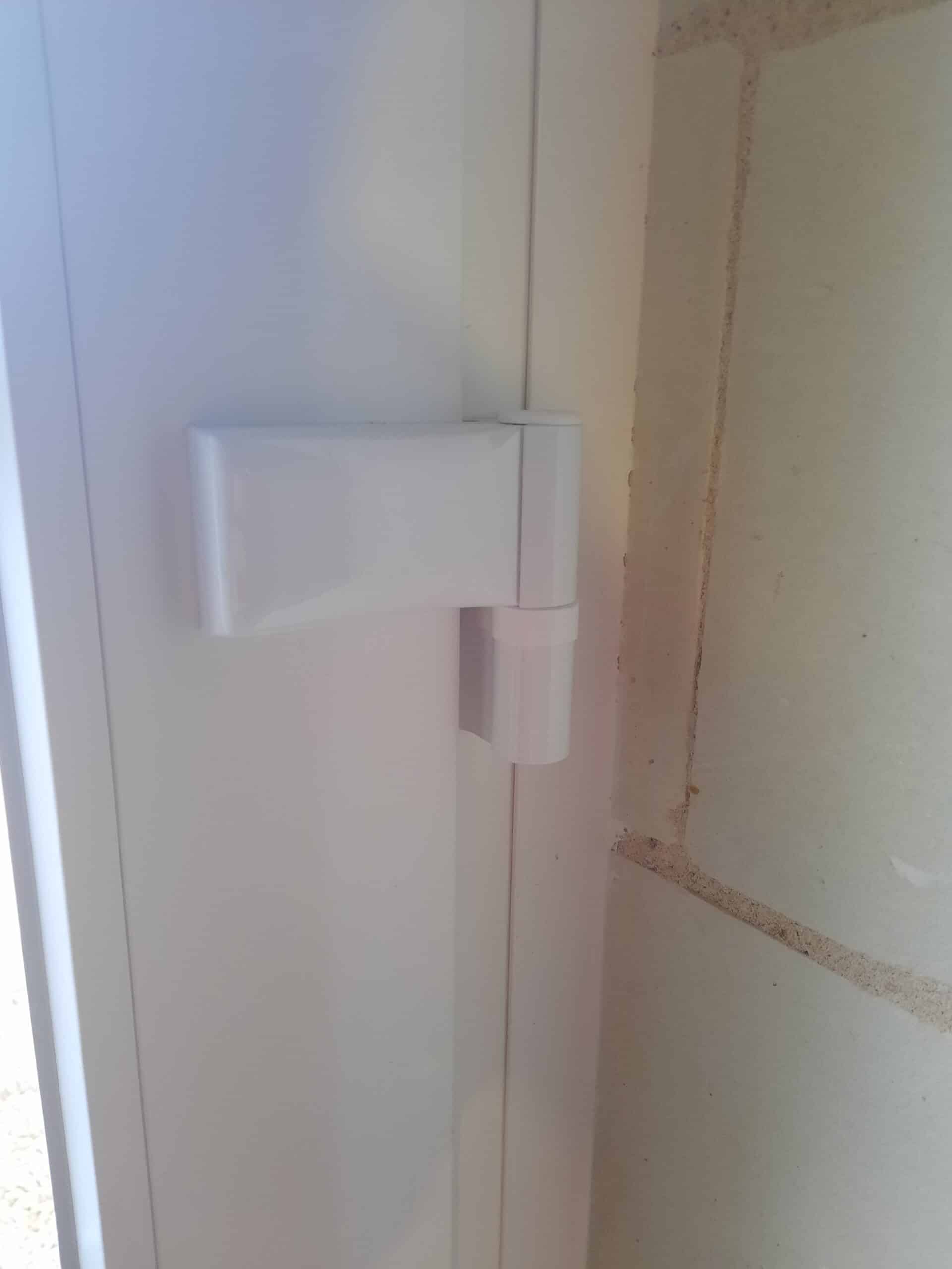 Zoom sur une paumelle renforcée blanche montée sur porte d’entrée PVC.