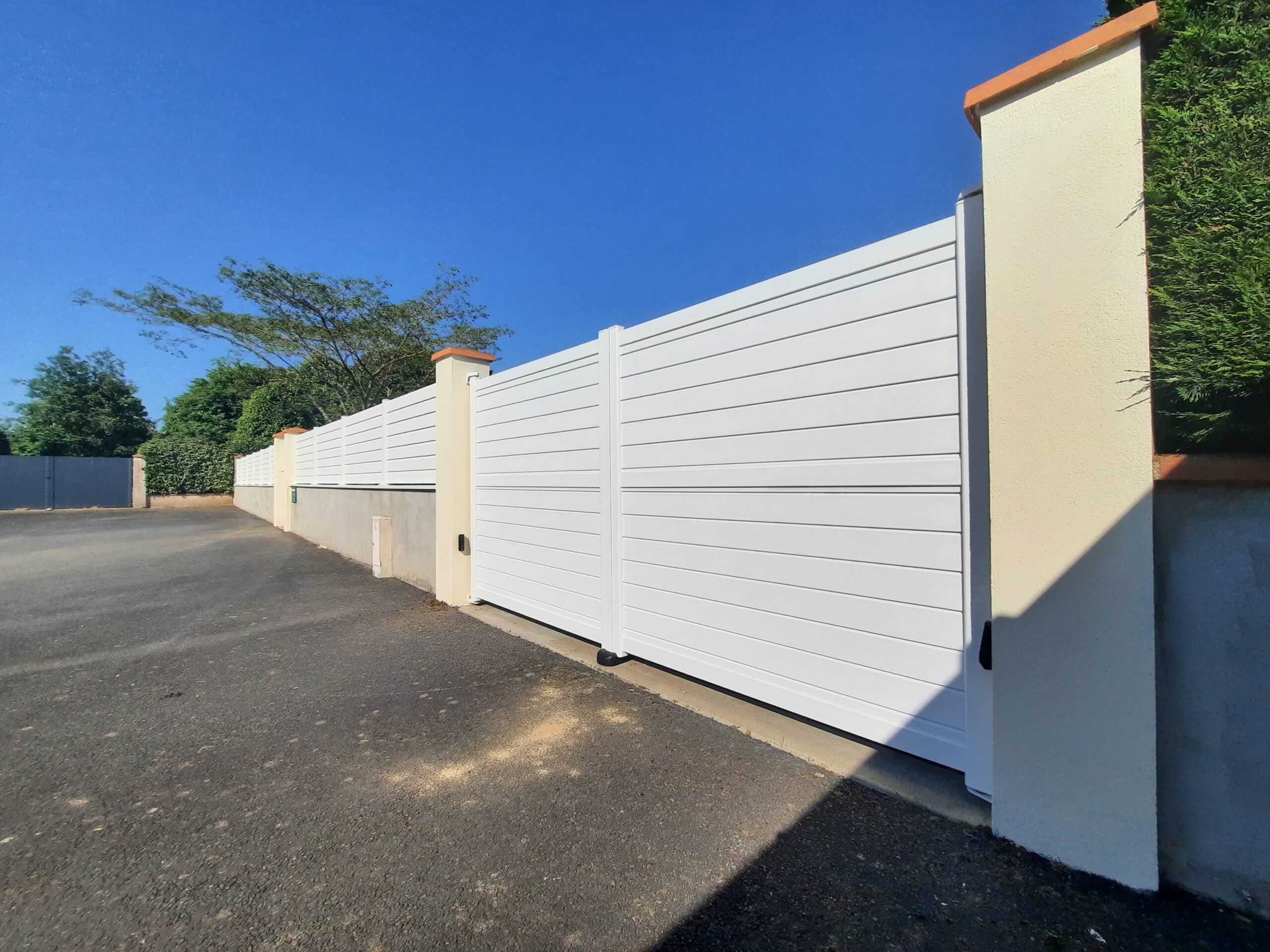 Portail aluminium battant blanc installé à Lys-Haut-Layon, modèle plein ajouré motorisé.