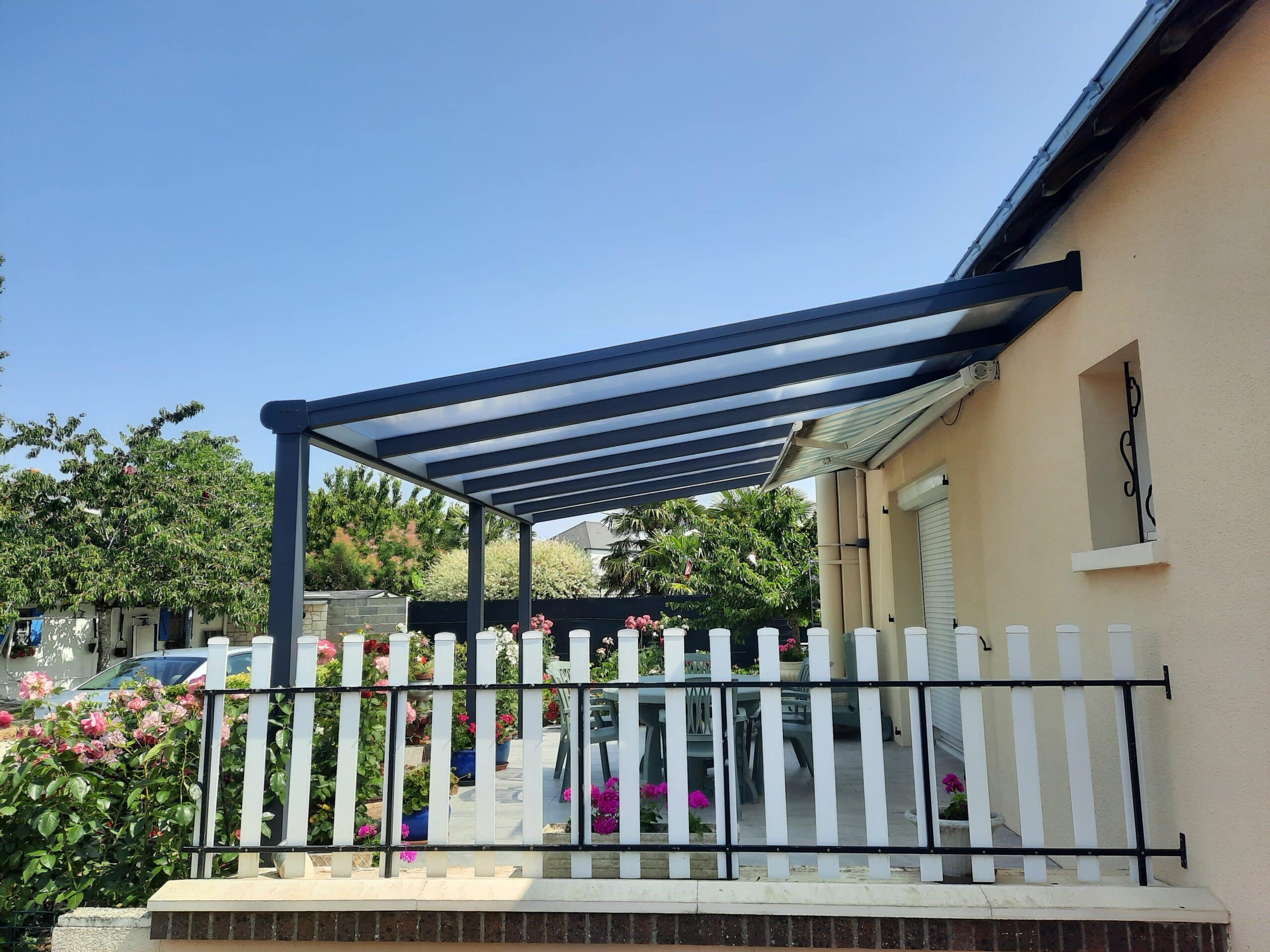 Pergola à toit fixe installée à Saumur sur terrasse avec jardin fleuri.