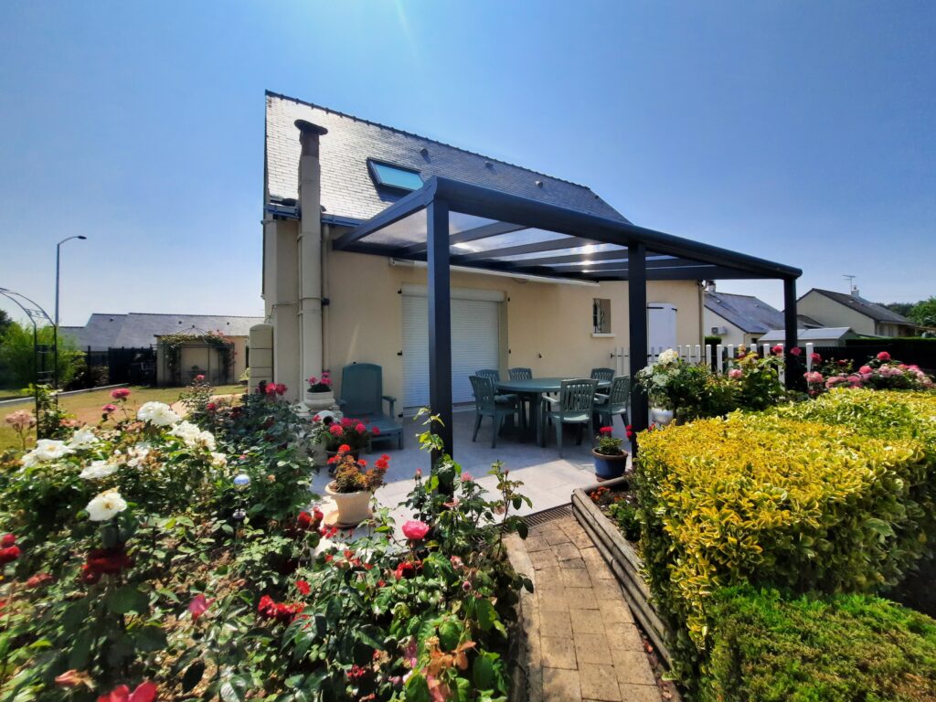Grande pergola aluminium à toit fixe dans un jardin fleuri à Saumur.