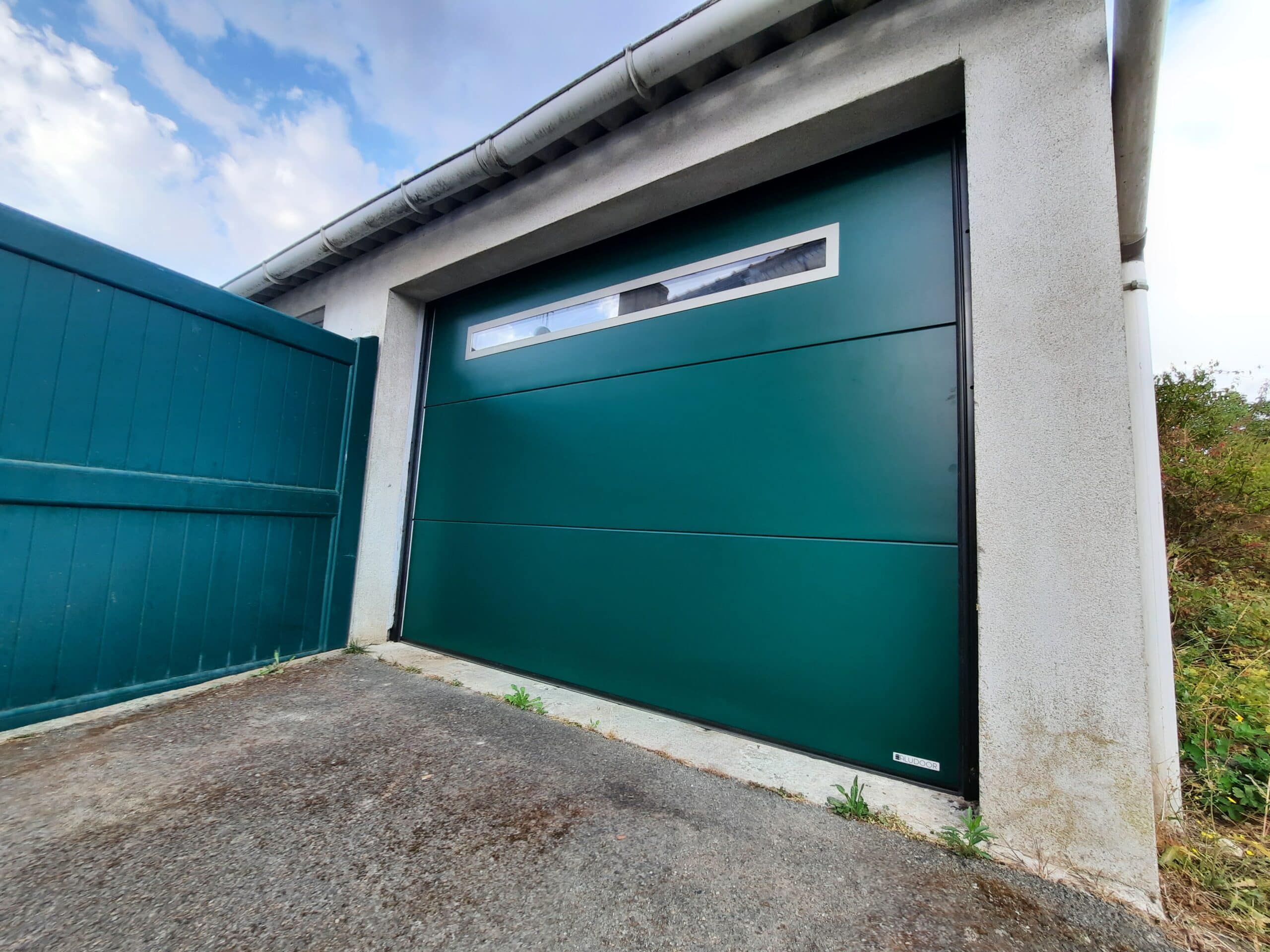 Vue latérale d’une porte de garage sectionnelle motorisée en acier à Le Pin